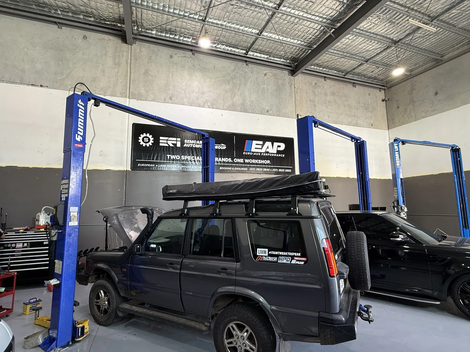 Land Rover Discovery with roof tent under the SemCar and Euro-Aus banner in the Capalaba workshop